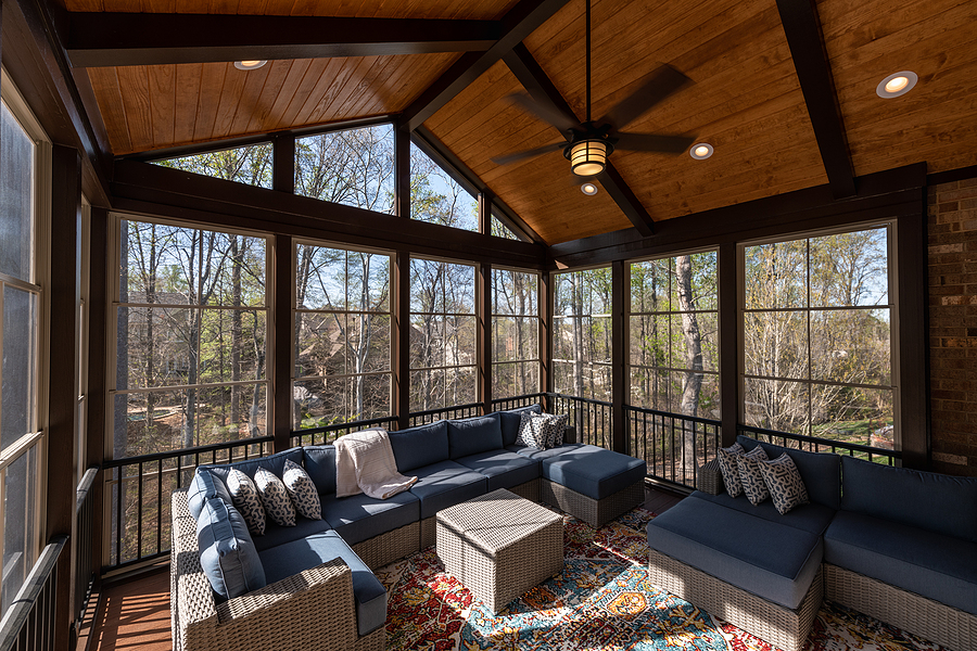 Contemporary screened porch in springtime, full of blooms trees in the background.